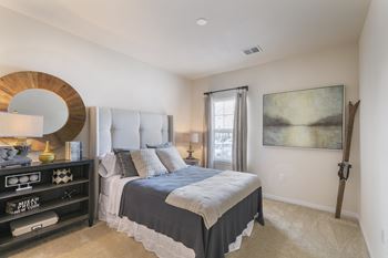 A bedroom with a large bed and a painting on the wall.